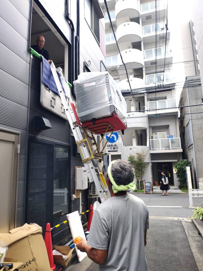 冷蔵庫を電動リフトで荷揚げ中の写真