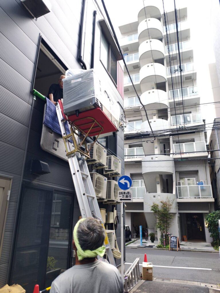 冷蔵庫を電動リフトで荷揚げしている写真